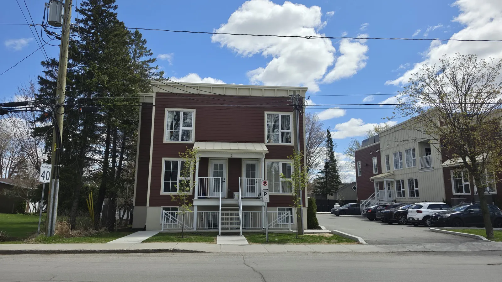 Façade d’un bâtiment de logements : parement rouge à panneaux verticaux, balcons et entrées individuelles