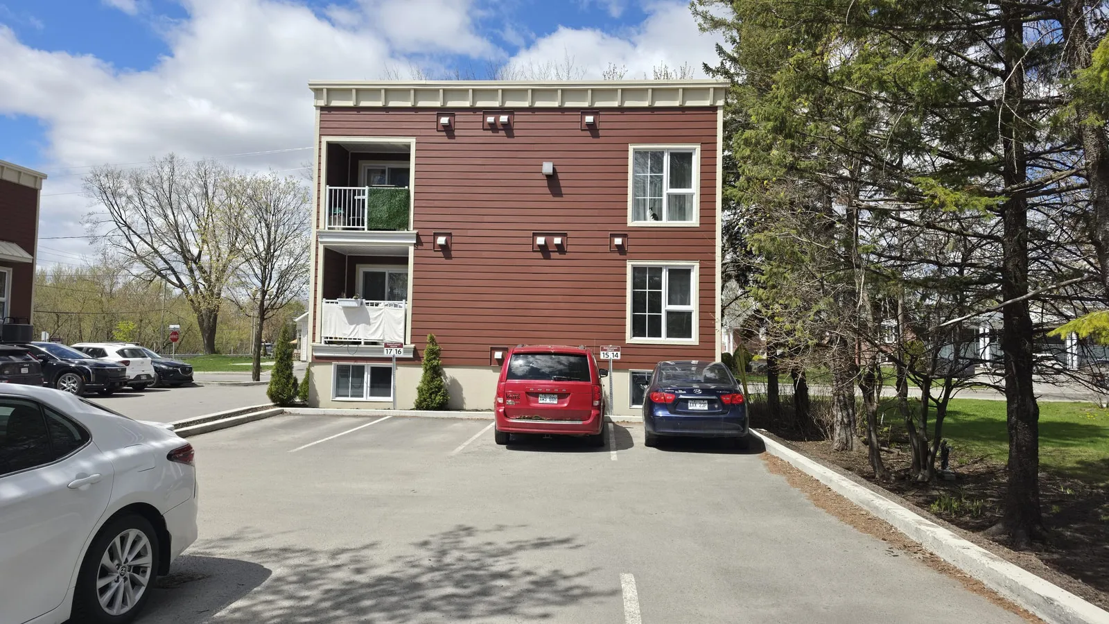 Vue arrière d’un bâtiment de logements et de son stationnement, à la fin des travaux