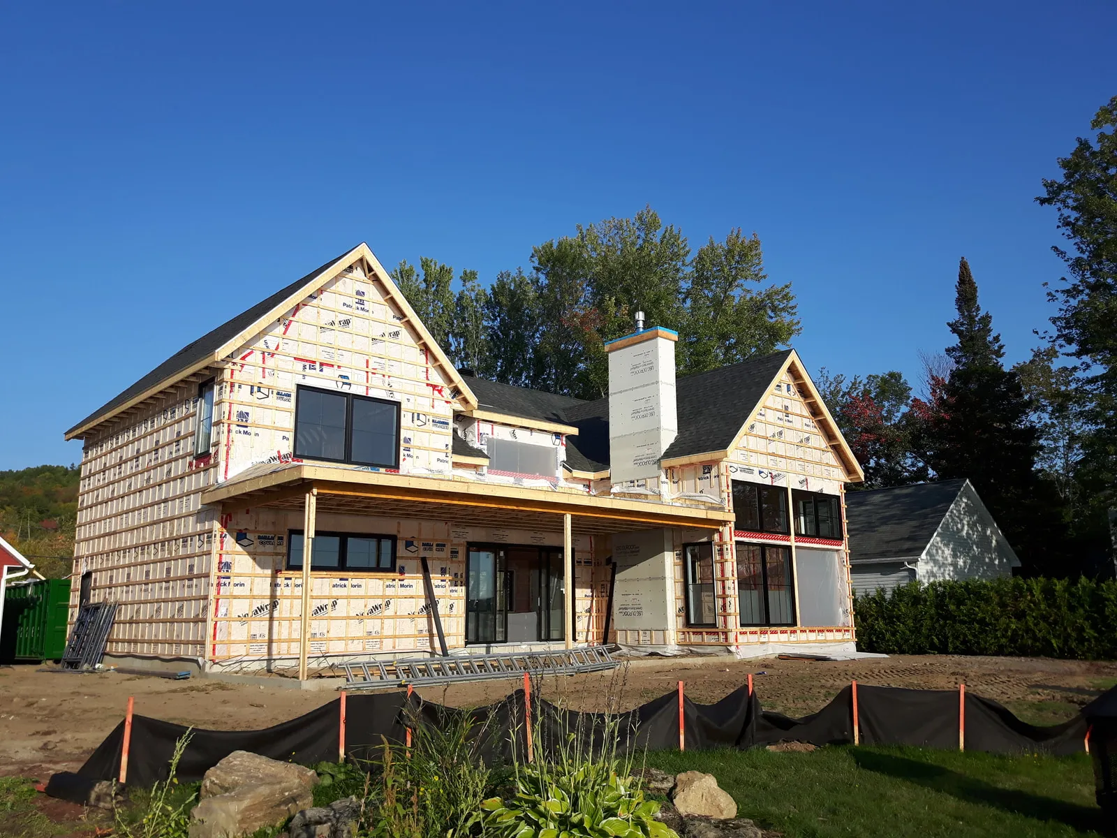 Façade avec galerie couverte en bois en construction sous une toiture noire