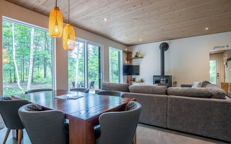 Salon-salle à manger du chalet LEED de Saint-Côme avec vue panoramique sur la forêt