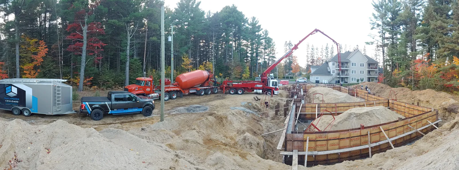 Coulée des fondations du 4-plex : coffrages, pompe à béton et terrain excavé