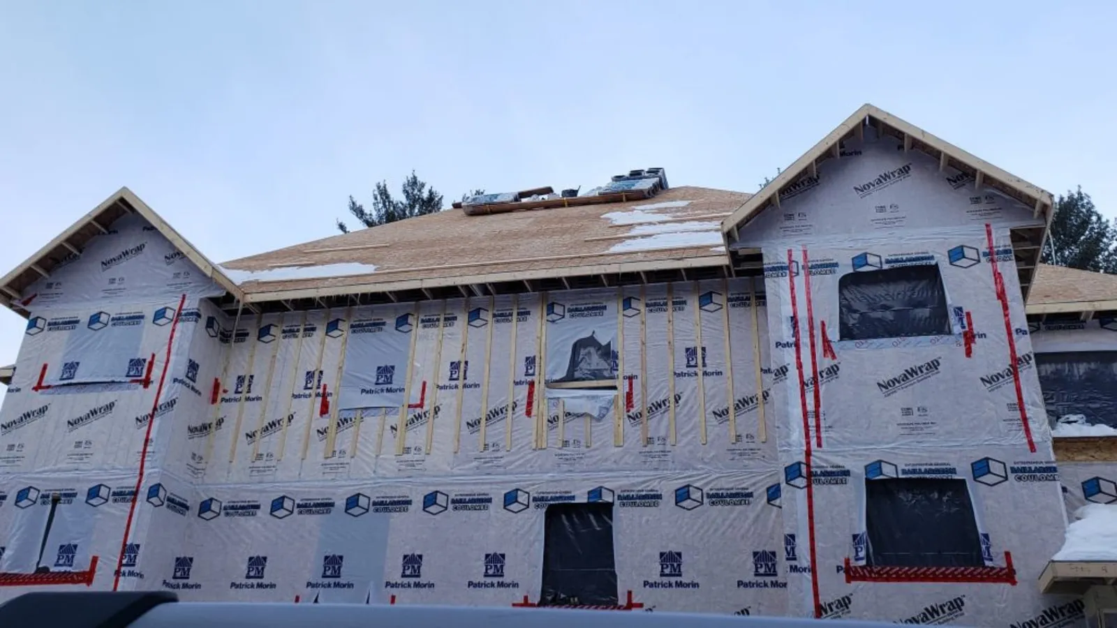 Façade sous membrane pare-air NovaWrap, joints rubanés de rouge et fourrures verticales, pontage de toit en panneaux posé