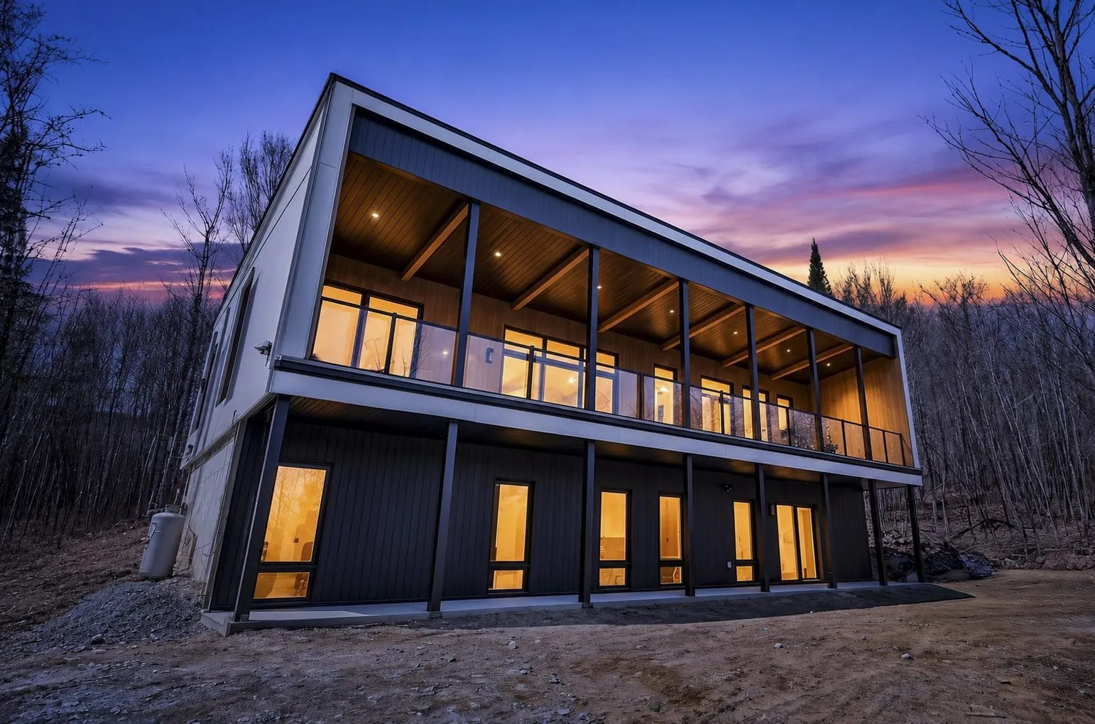 Le chalet au crépuscule, terrasse et intérieurs illuminés sur fond de ciel violet