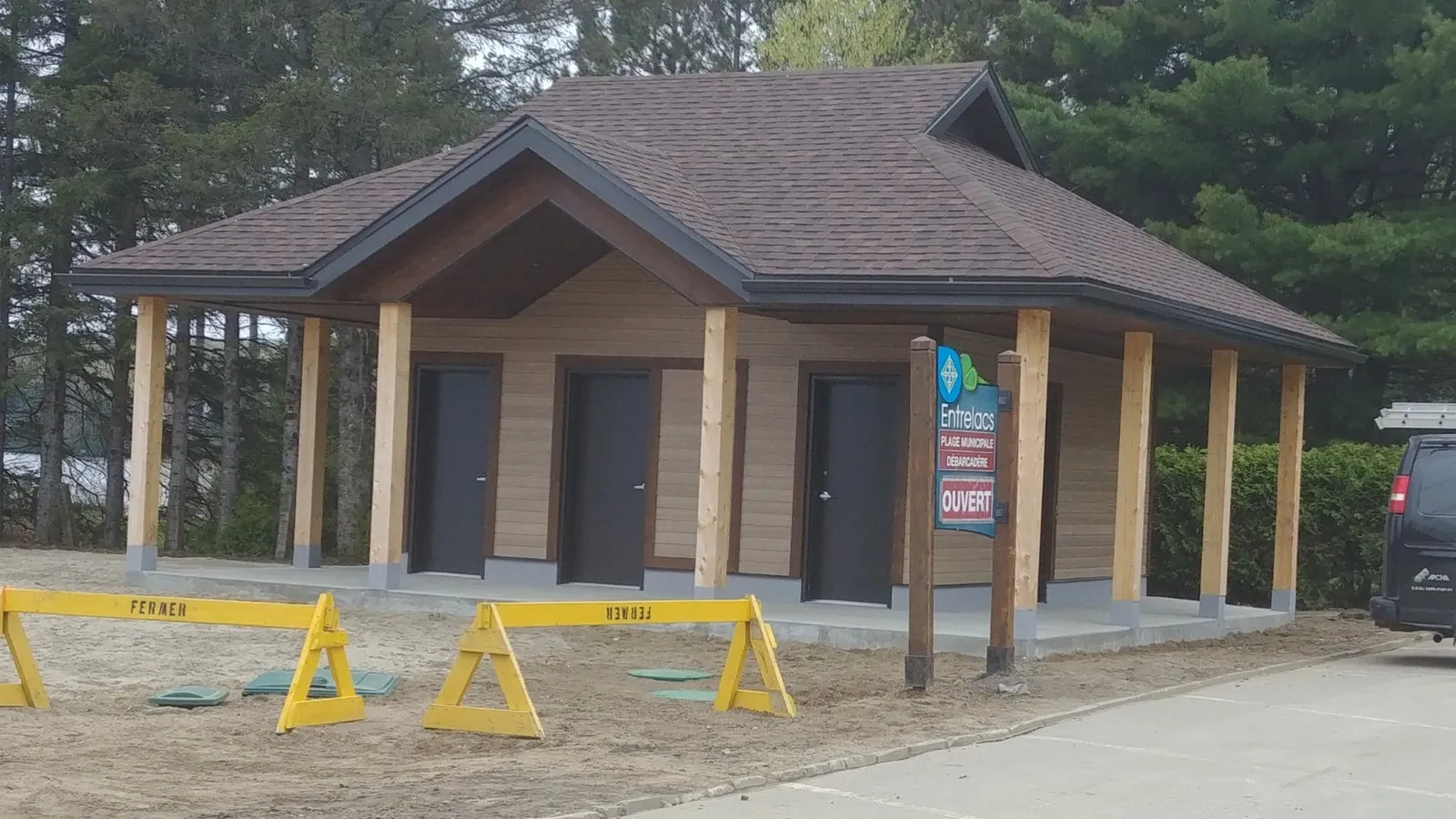 Le pavillon vu de face : trois portes foncées sous la galerie et colonnes de bois clair