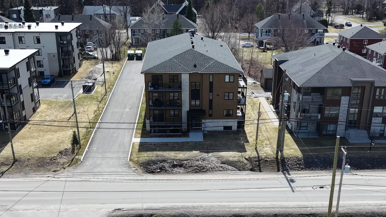 Vue aérienne large de l’immeuble entouré des bâtiments voisins, la rue au premier plan