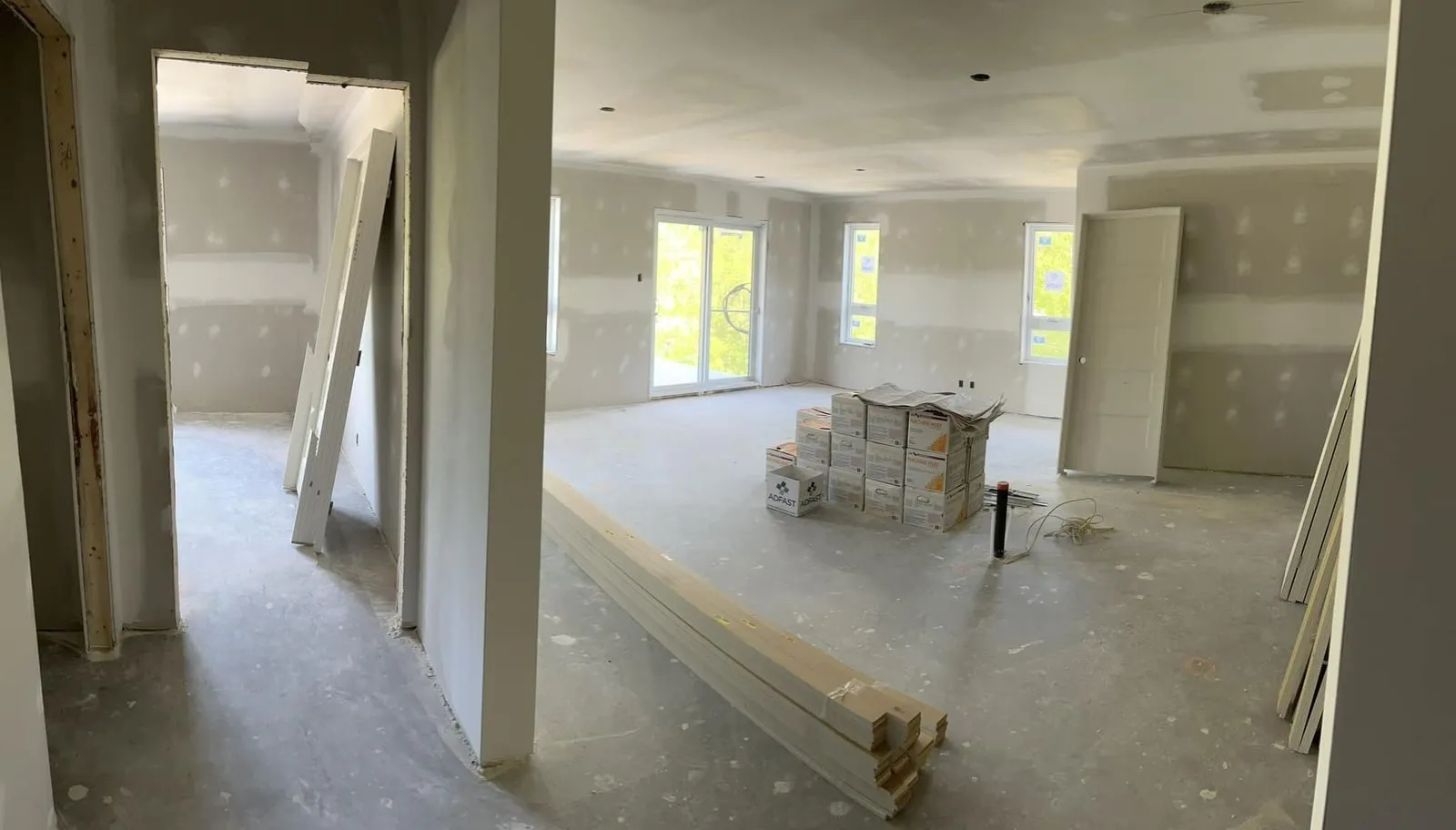 Aire de vie ouverte d’un logement, porte-patio et fenêtres installés, cloisons de gypse en place