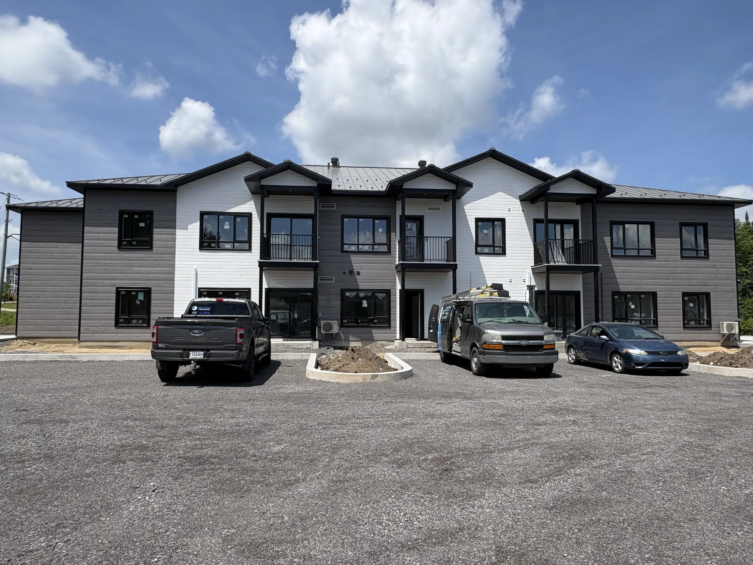 Façade de l'immeuble gris et blanc vue de face : une suite de pignons et des entrées individuelles au rez-de-chaussée