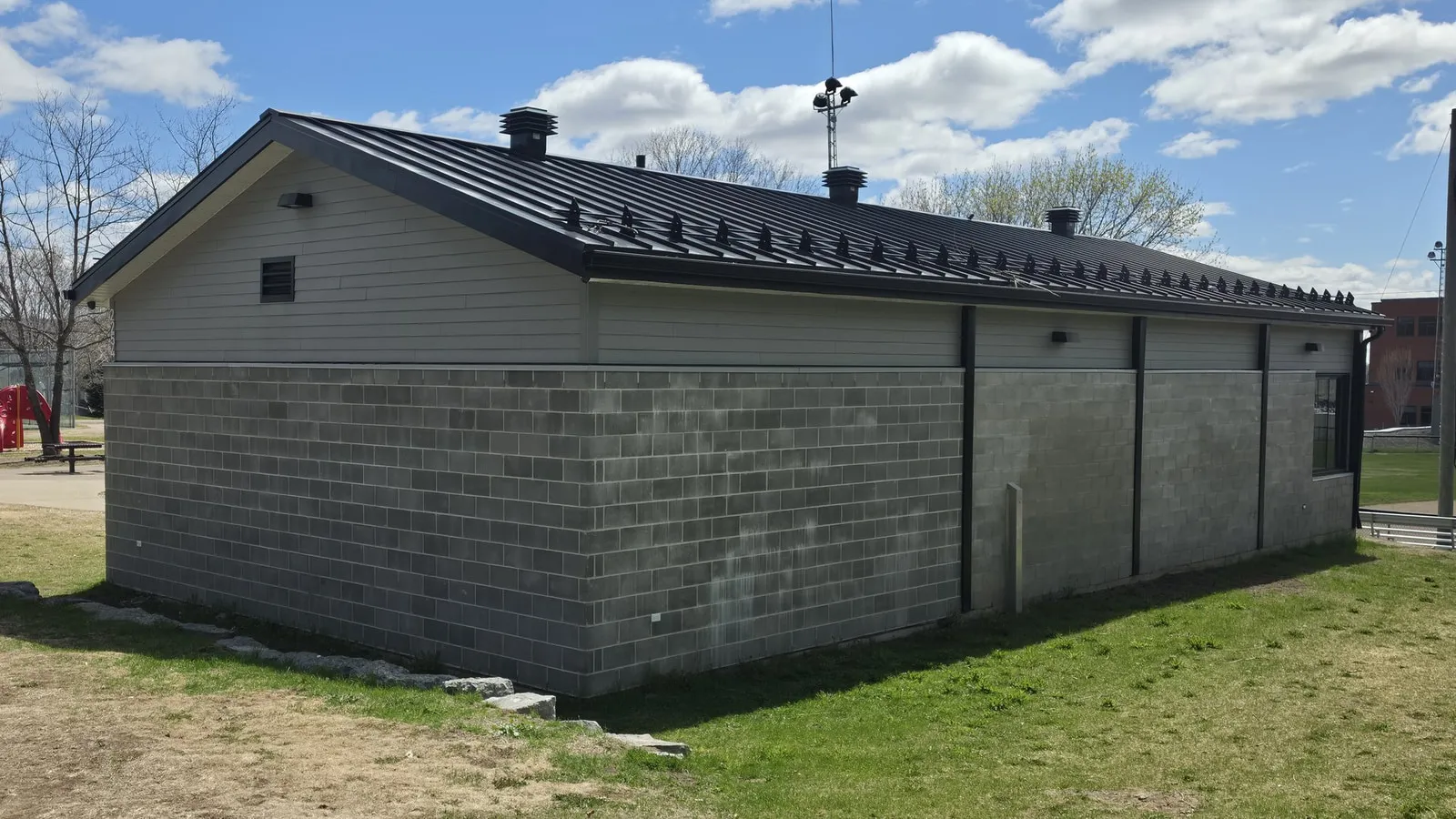 Le volume agrandi vu de côté : murs de blocs de béton et longue toiture en pente d’un seul tenant