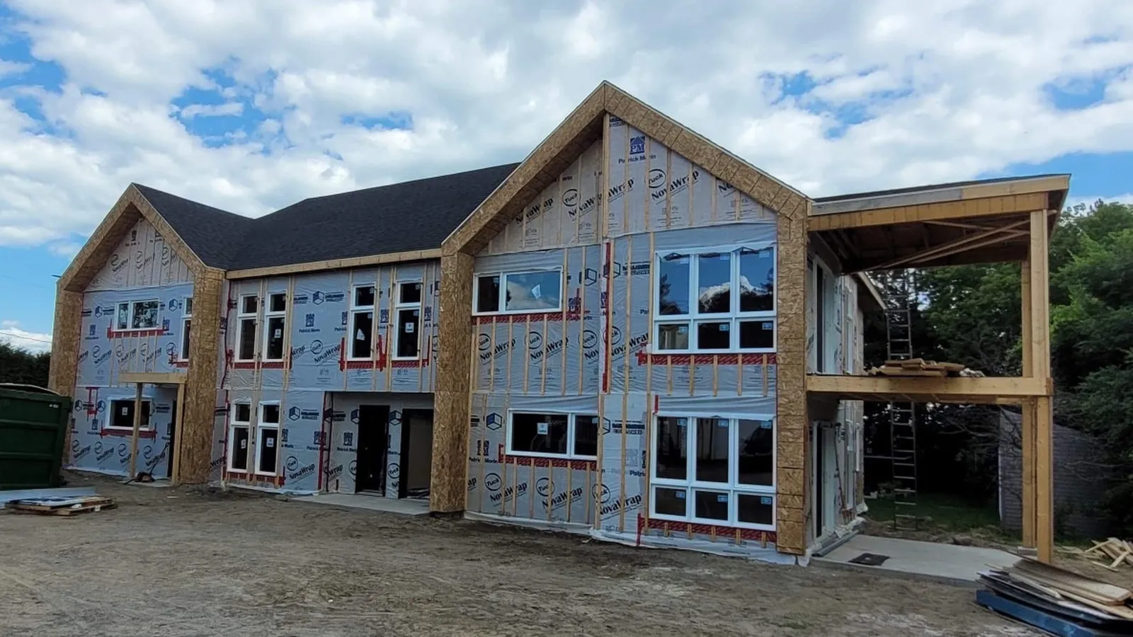 Enveloppe du bâtiment en cours de fermeture : pare-air posé, fenêtres installées et structure des balcons