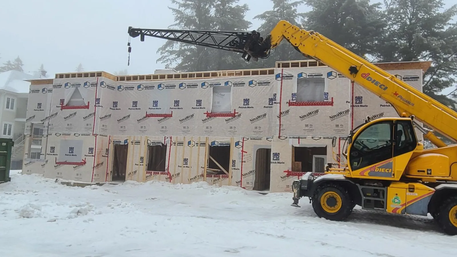 Ouvertures de portes alignées au rez-de-chaussée, façade sous membrane pare-air et chariot télescopique à droite
