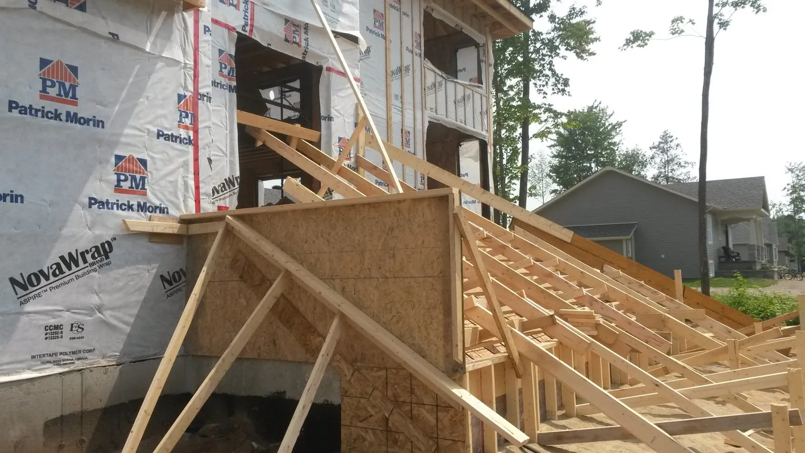 Coffrage de bois de l’escalier de béton devant la façade encore sous membrane pare-air