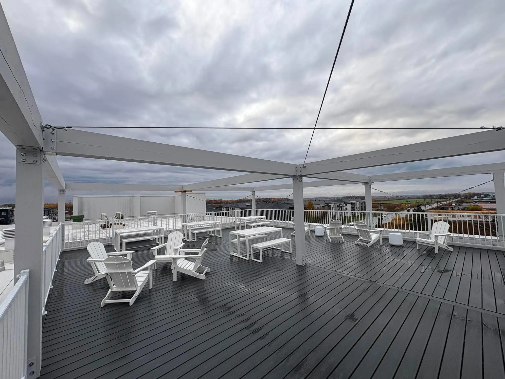 Terrasse en bois sur le toit, avec pergola blanche, chaises de jardin et garde-corps clair