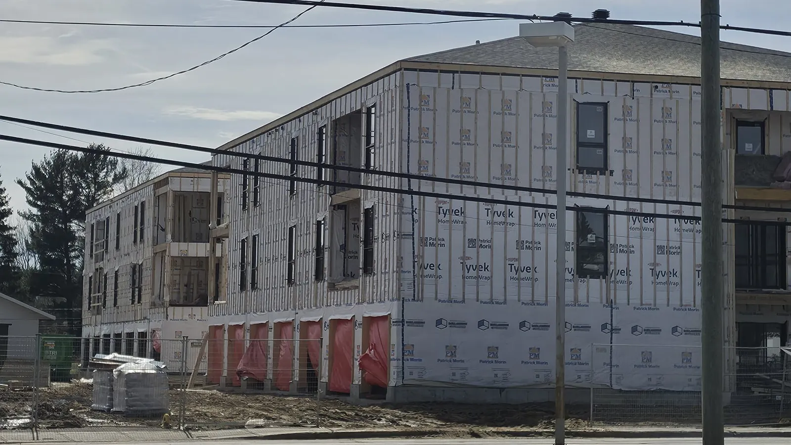 Vue d’angle du bâtiment en chantier, membrane pare-air posée et ouvertures en place