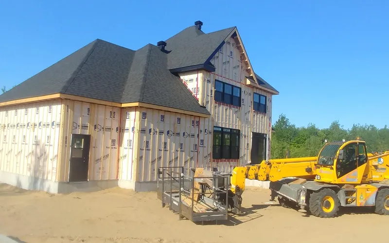 Maison neuve en chantier : toiture posée, fenêtres installées et murs fermés par la membrane pare-air