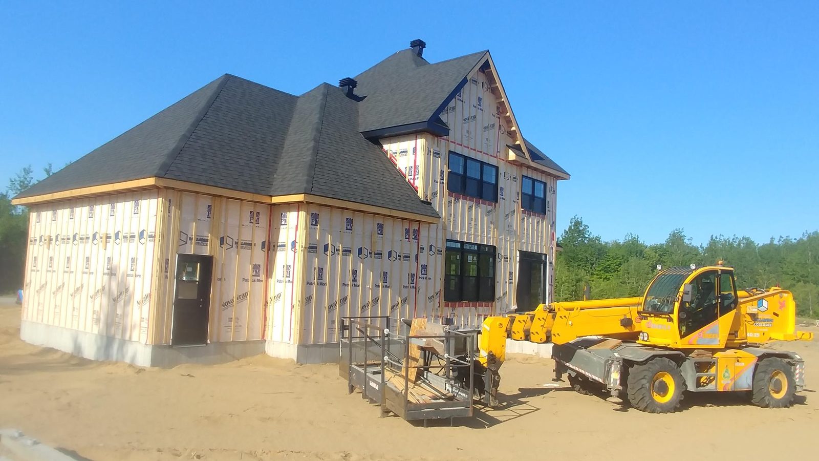 Maison neuve en chantier : toiture posée, fenêtres installées et murs fermés par la membrane pare-air